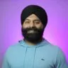 Smiling man with a black turban and beard against a purple gradient background.