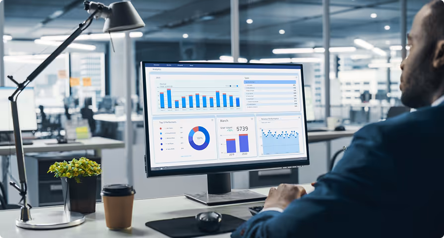 Man working on a computer displaying sales and user analytics charts in a modern office.